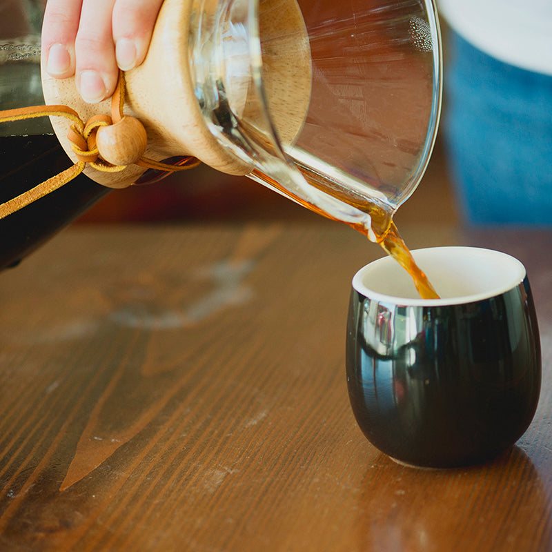 Brewed coffee poured from Chemex into black mug